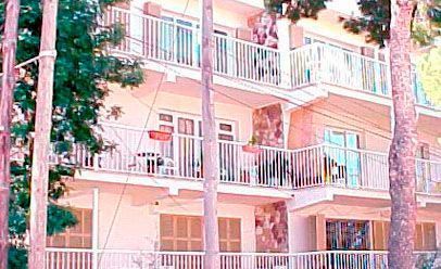 Un gran edificio de apartamentos con balcones rodeado de árboles.