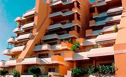 Un gran edificio de apartamentos con muchos balcones y árboles en el frente.