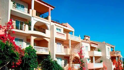 Una hilera de edificios de apartamentos con balcones y flores delante de ellos.