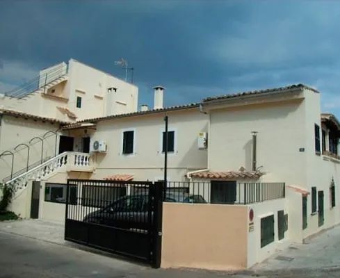 Un edificio blanco con un coche negro aparcado delante.