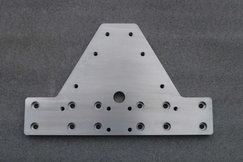 Graue Metallhalterung mit mehreren Bohrlöchern auf grauem Hintergrund