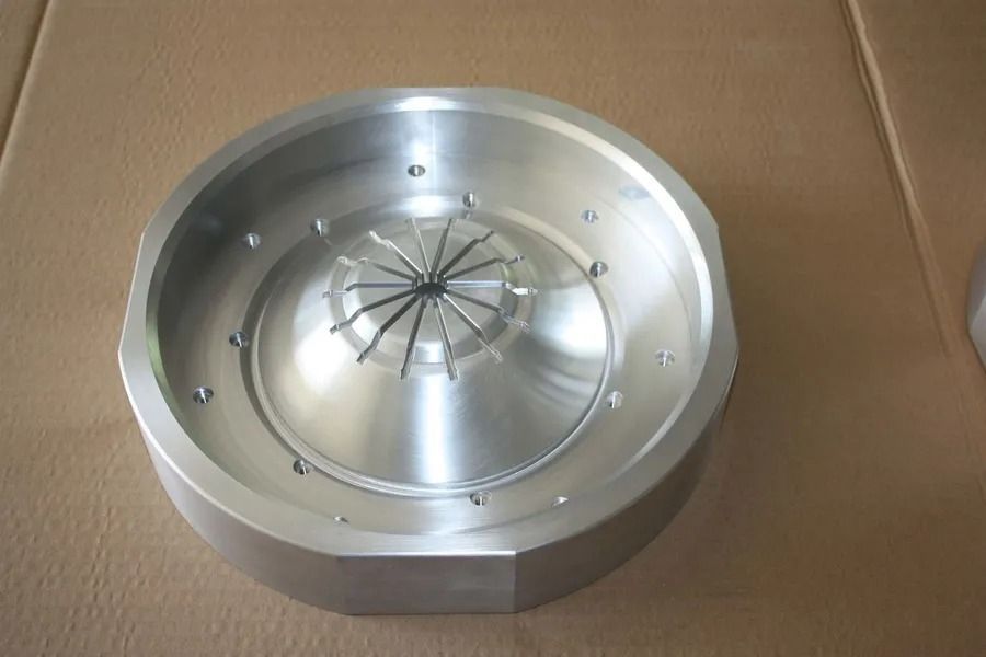 Rundes mechanisches Metallteil mit zentraler, federbelasteter Nabe auf Kartonoberfläche