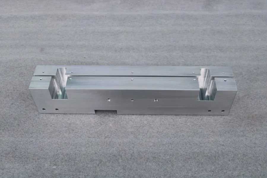 Silberne Metallhalterung mit zwei weissen Klemmen auf grauem Teppichboden