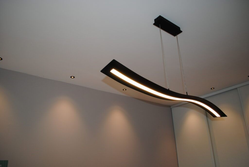 Luminaire suspendu moderne noir en forme de vague, fixé au plafond.