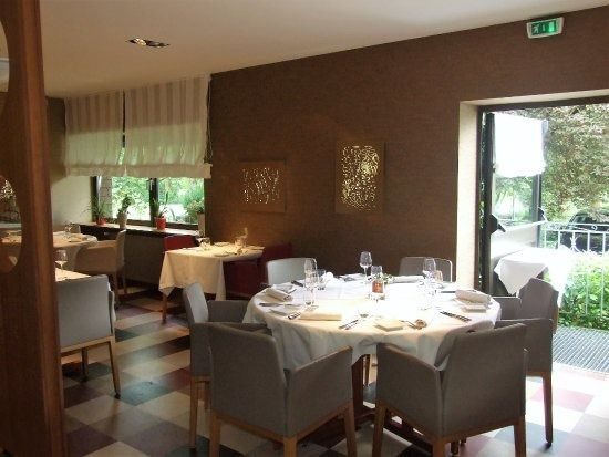 Intérieur d'un restaurant avec une table ronde dressée pour un repas, des murs bruns et de grandes fenêtres.