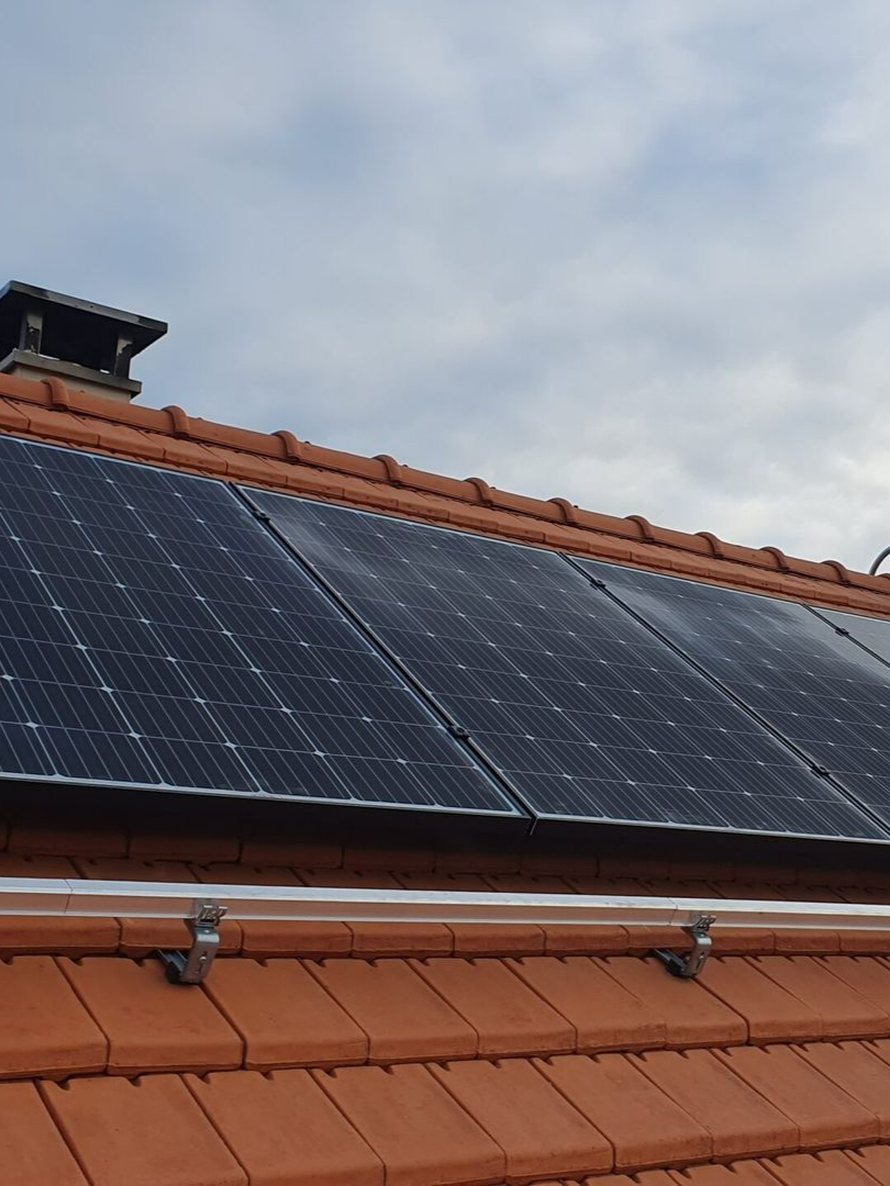 Des panneaux solaires installés sur un toit de tuiles rouges.