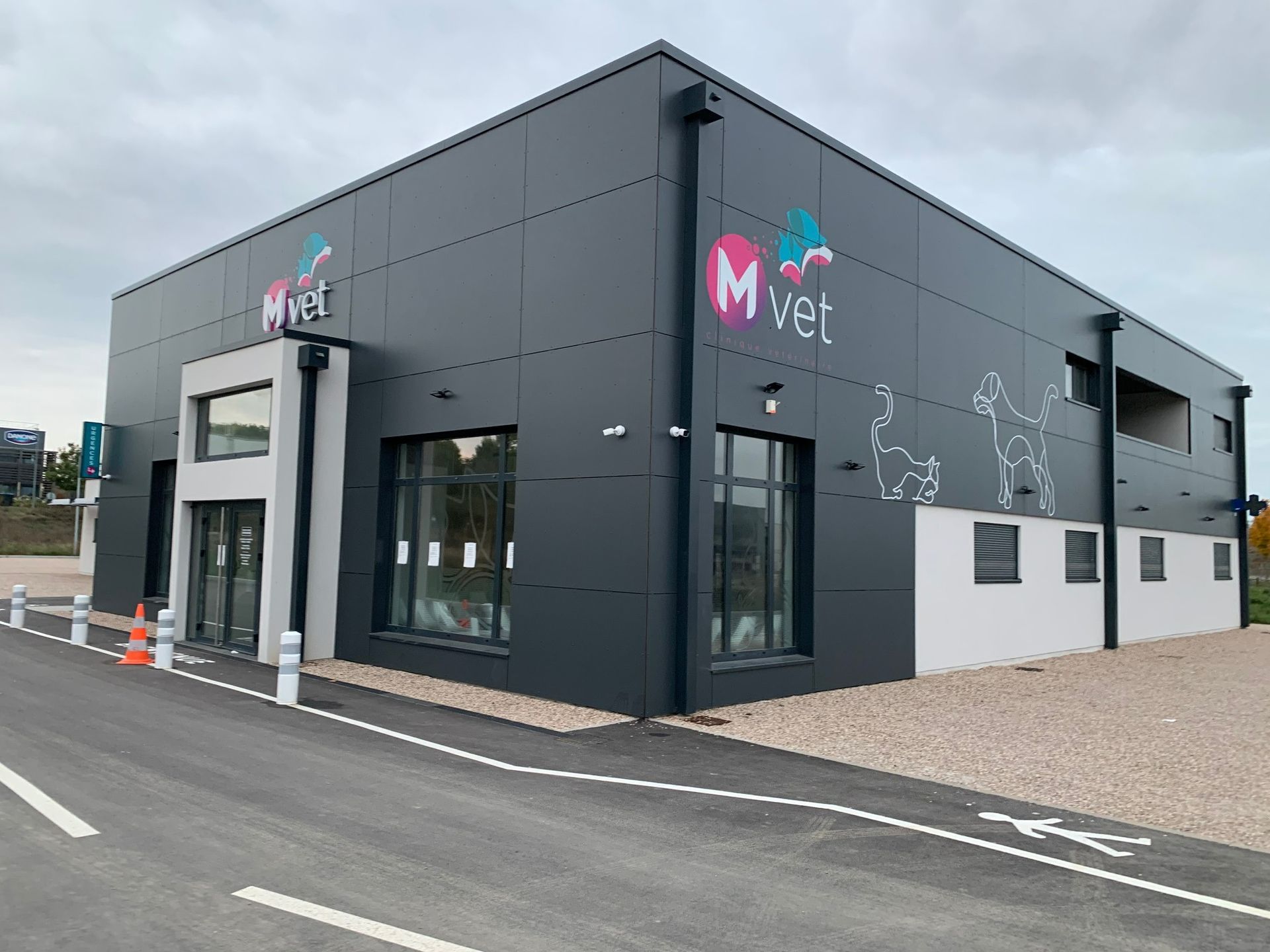 Bâtiment moderne gris avec le logo M Vet; extérieur d'une clinique vétérinaire.