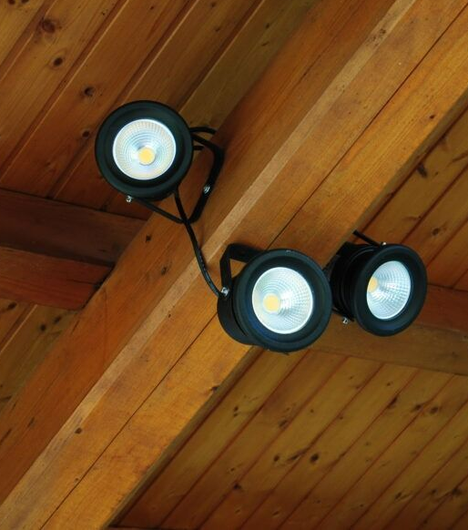Trois spots LED noirs, fixés au plafond en bois et orientés de manière à éclairer l'espace.