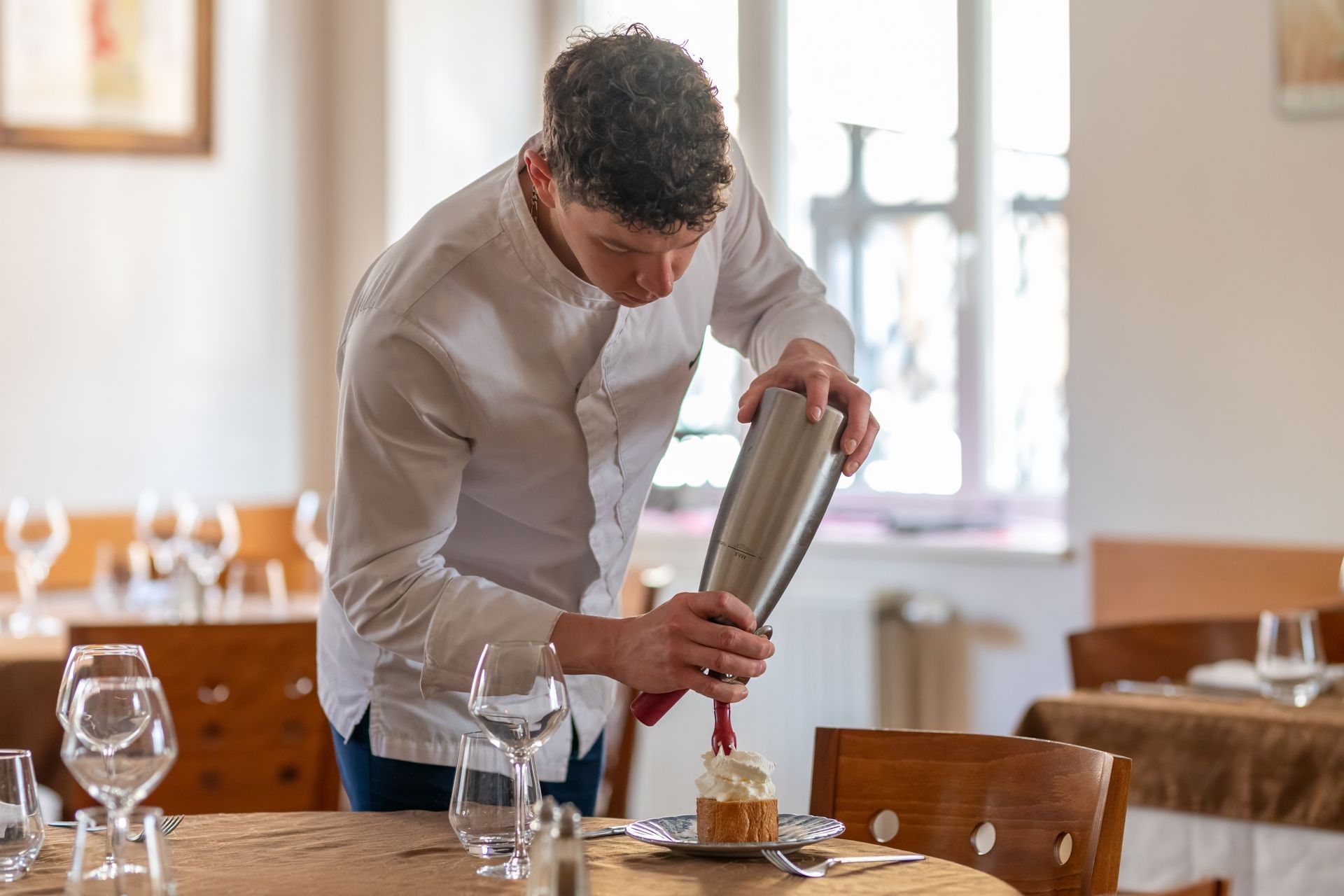 Cuisiner qui dépose un coulis de fruit sur une pâtisserie