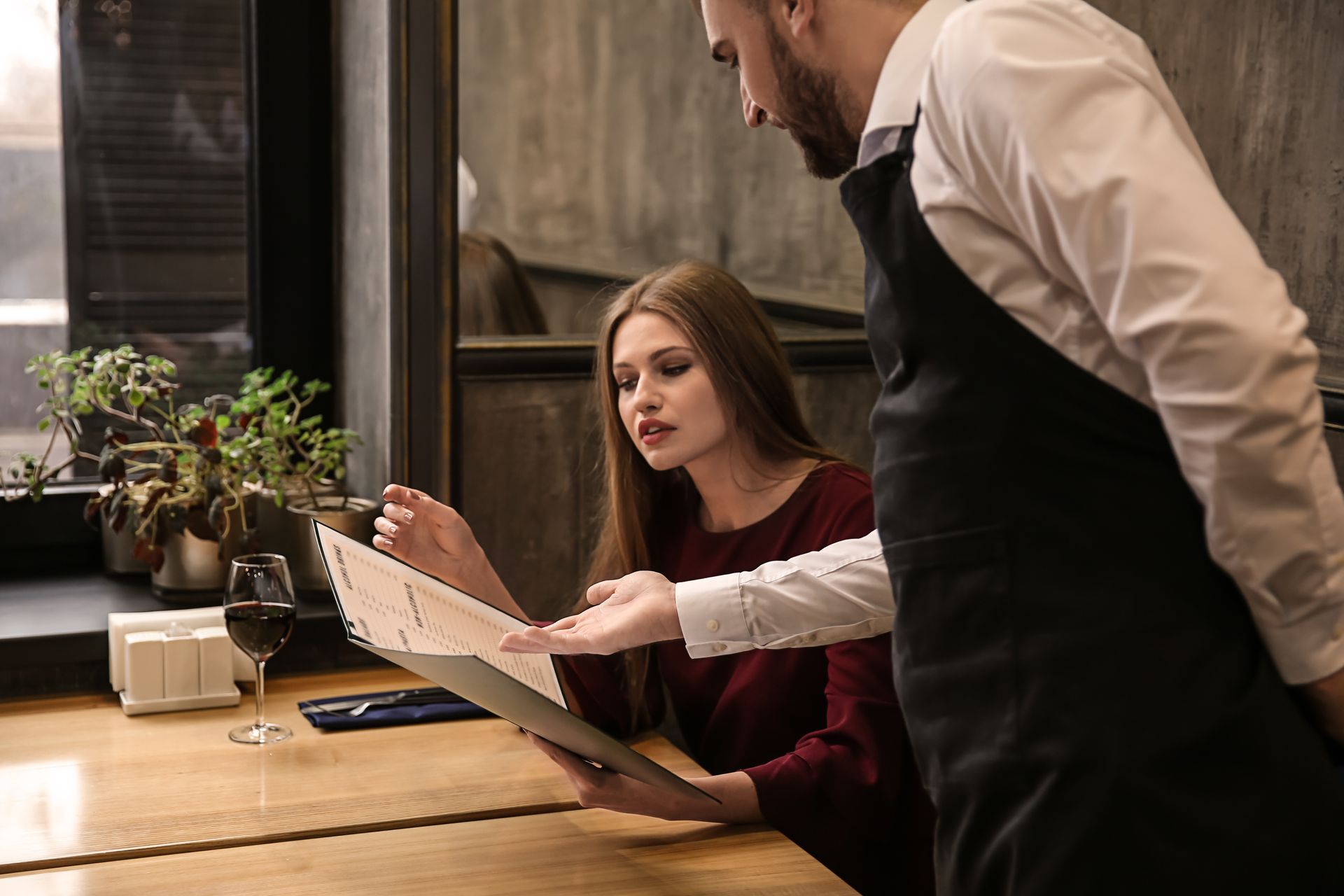 Serveur qui propose un menu à une jeune femme