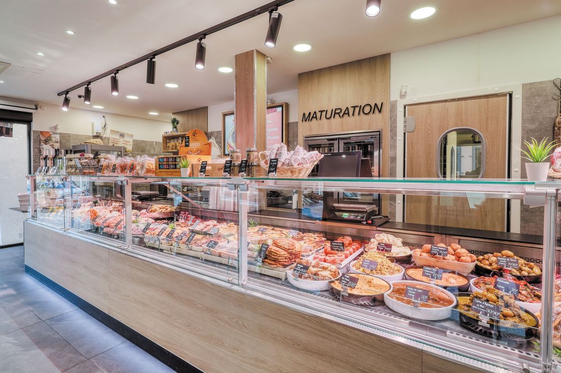 Vitrine de boulangerie avec assortiment de viennoiseries et de pains sous une lumière vive à l'intérieur d'un magasin