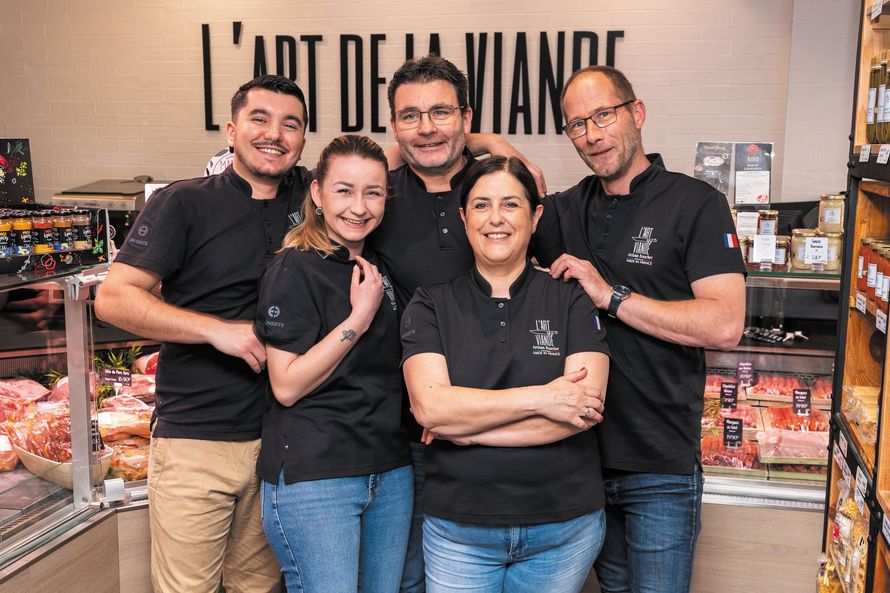 Cinq membres de l'équipe, vêtus de chemises noires, posent derrière le comptoir d'une boulangerie avec l'enseigne « L'ART DE LA VIANDE » en arrière-plan.