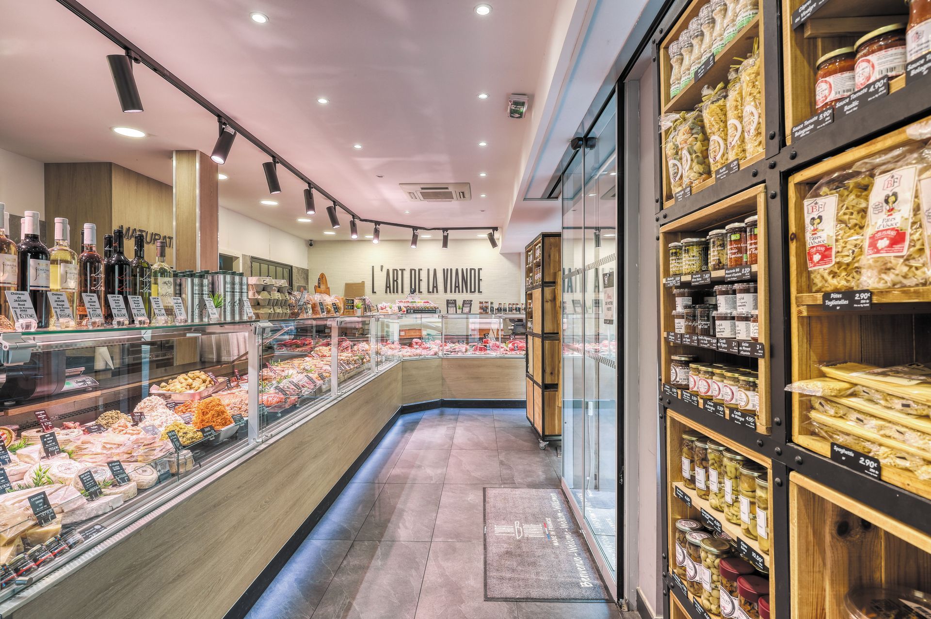 Épicerie fine lumineuse avec vitrines et étagères de produits emballés dans une allée étroite.