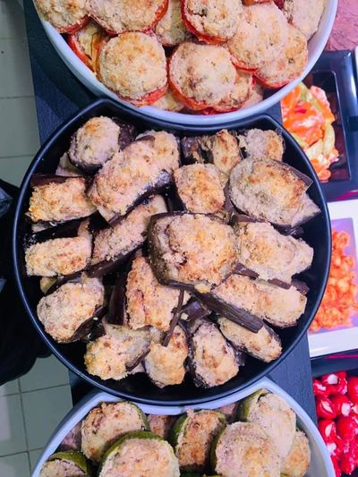 Plateaux de beignets et de raviolis frits disposés dans des plats ronds, accompagnés de légumes rouges.