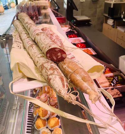 Vitrine de charcuterie présentant des saucisses et salamis suspendus.