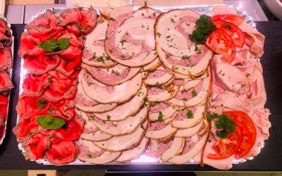 Assortiment de charcuteries et de garnitures disposées sur un plat de service agrémenté de roses roses.