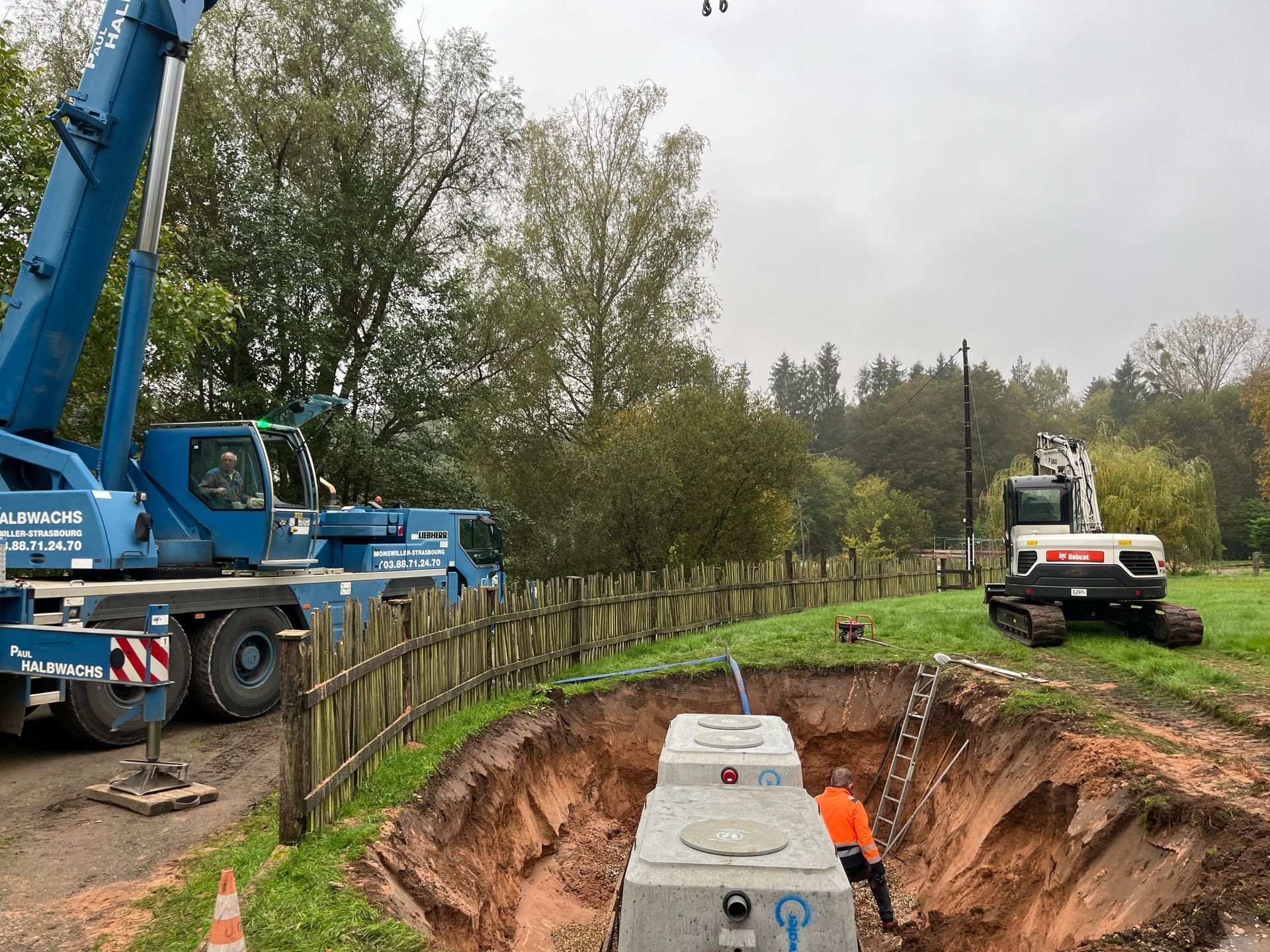 Deux microstations dans un trou derrière une barrière en bois.