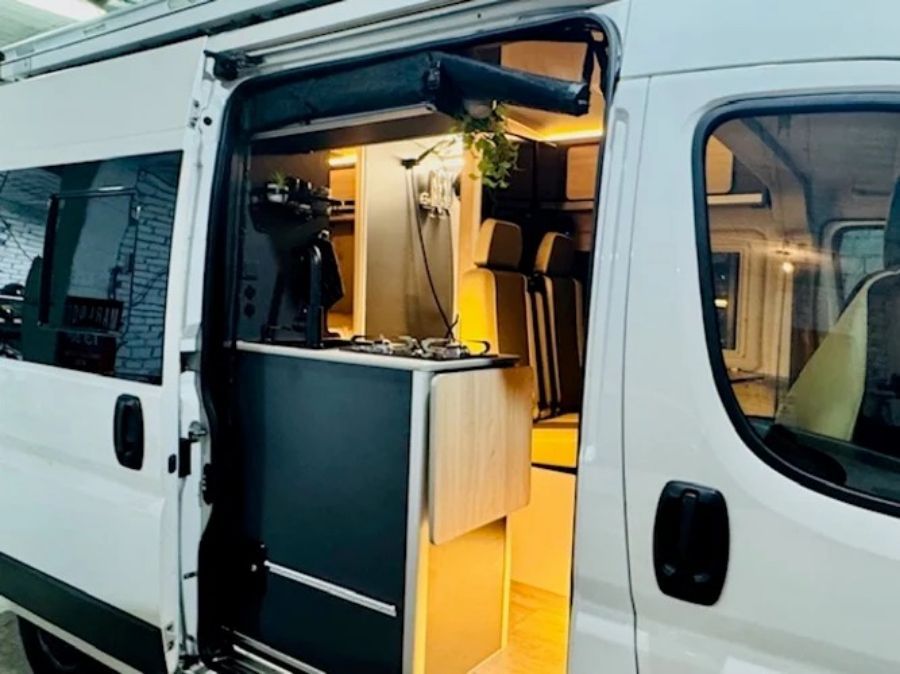 Furgoneta abierta con mostrador plegable e iluminación interior cálida, que muestra un espacio de trabajo móvil y compacto.
