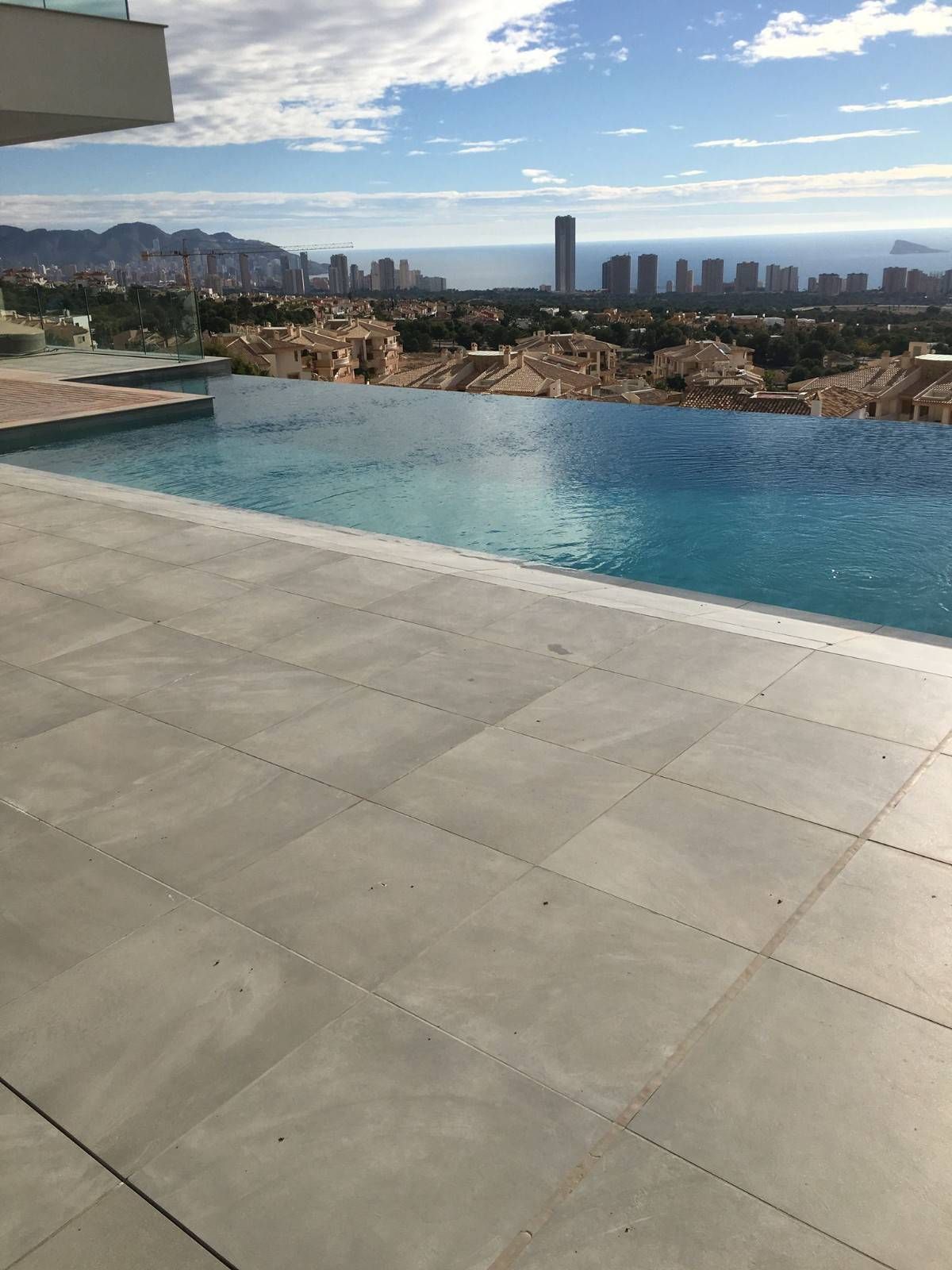 Piscina infinita con vista al horizonte de la ciudad en un día soleado.