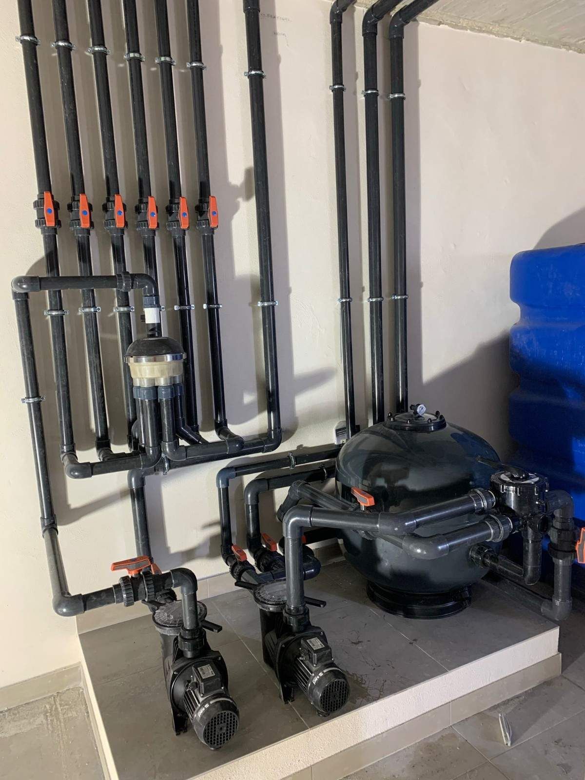 Sistema de plomería de piscina negra con válvulas y filtro.