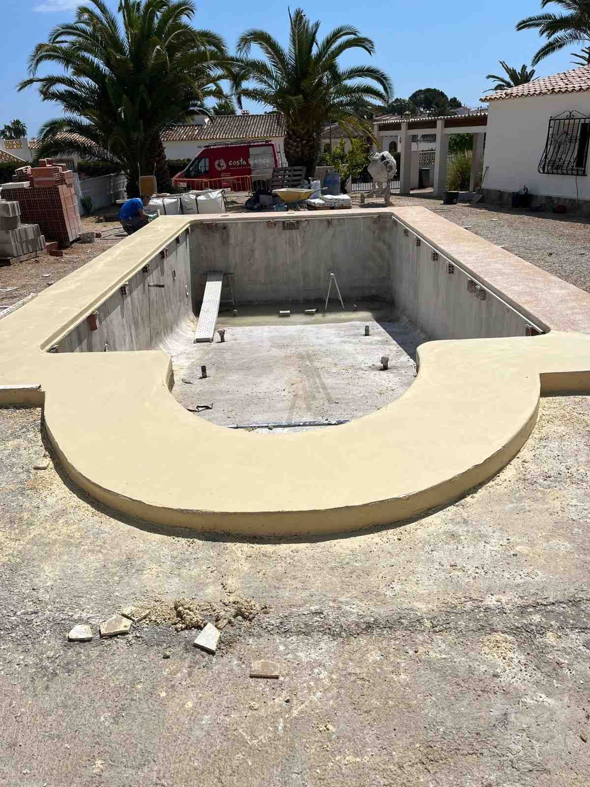 Piscina vacía en construcción, de hormigón con borde color canela.