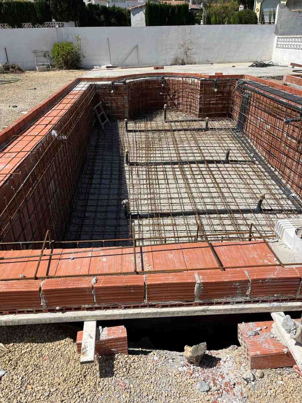 Construcción de piscina de obra rectangular de ladrillo con estructura de varilla corrugada.