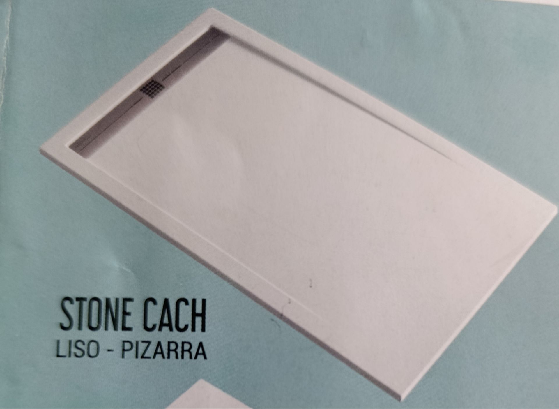 Tapa metálica de desagüe en una ducha con azulejos. Agua sobre los azulejos gris oscuro.