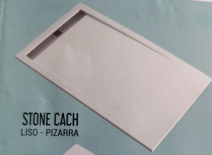Tapa metálica de desagüe en una ducha con azulejos. Agua sobre los azulejos gris oscuro.