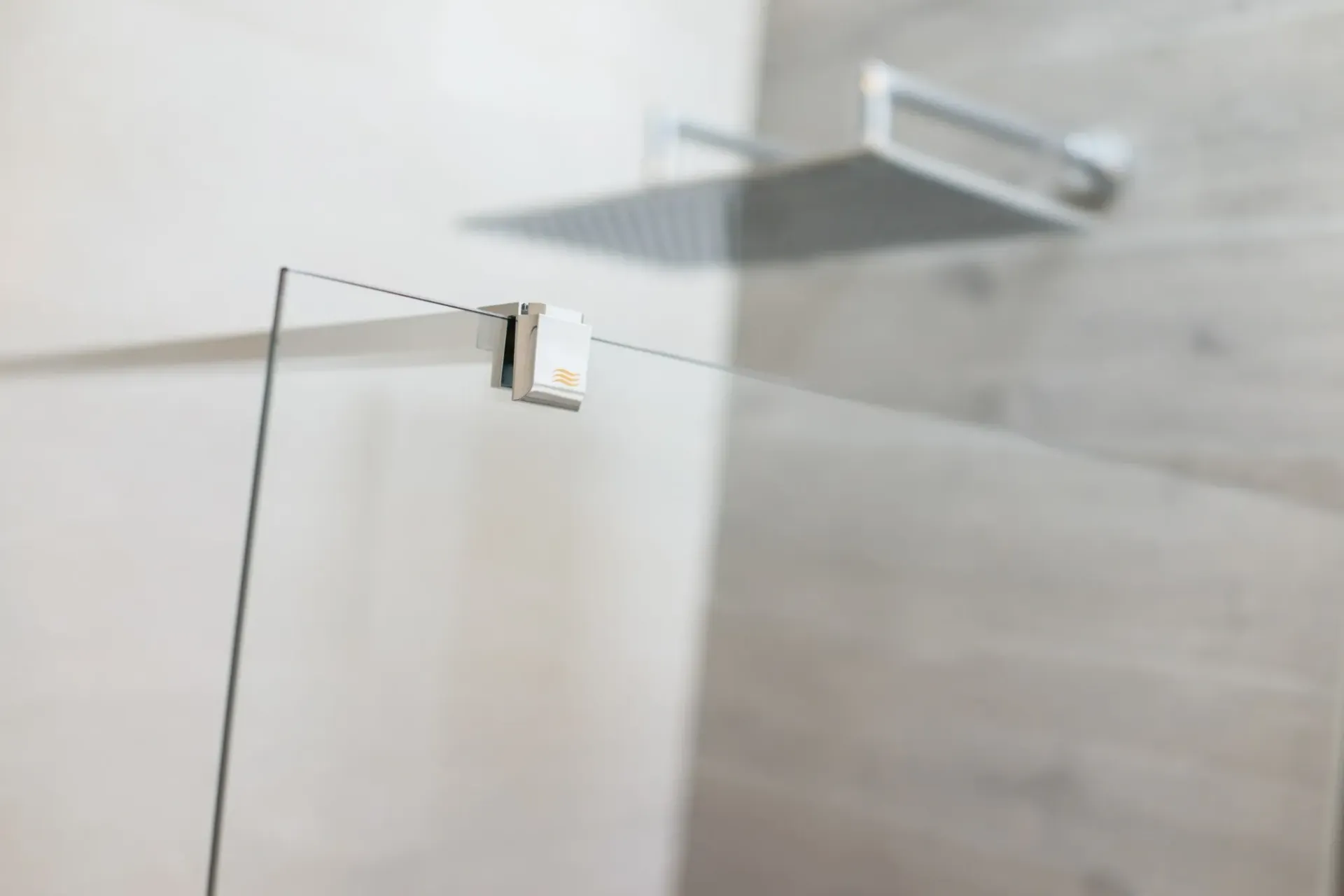 Ducha con puerta de cristal, cabezal de ducha metálico y paredes revestidas de azulejos en tonos claros.