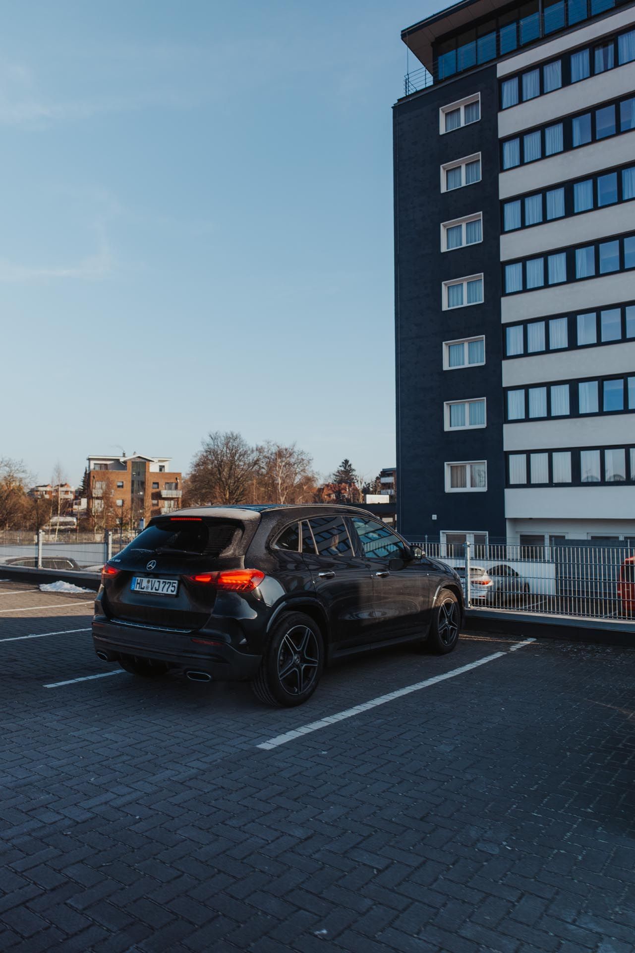 Ein schwarzer Geländewagen parkt an einem sonnigen Tag auf einem Parkplatz neben einem hohen Gebäude.