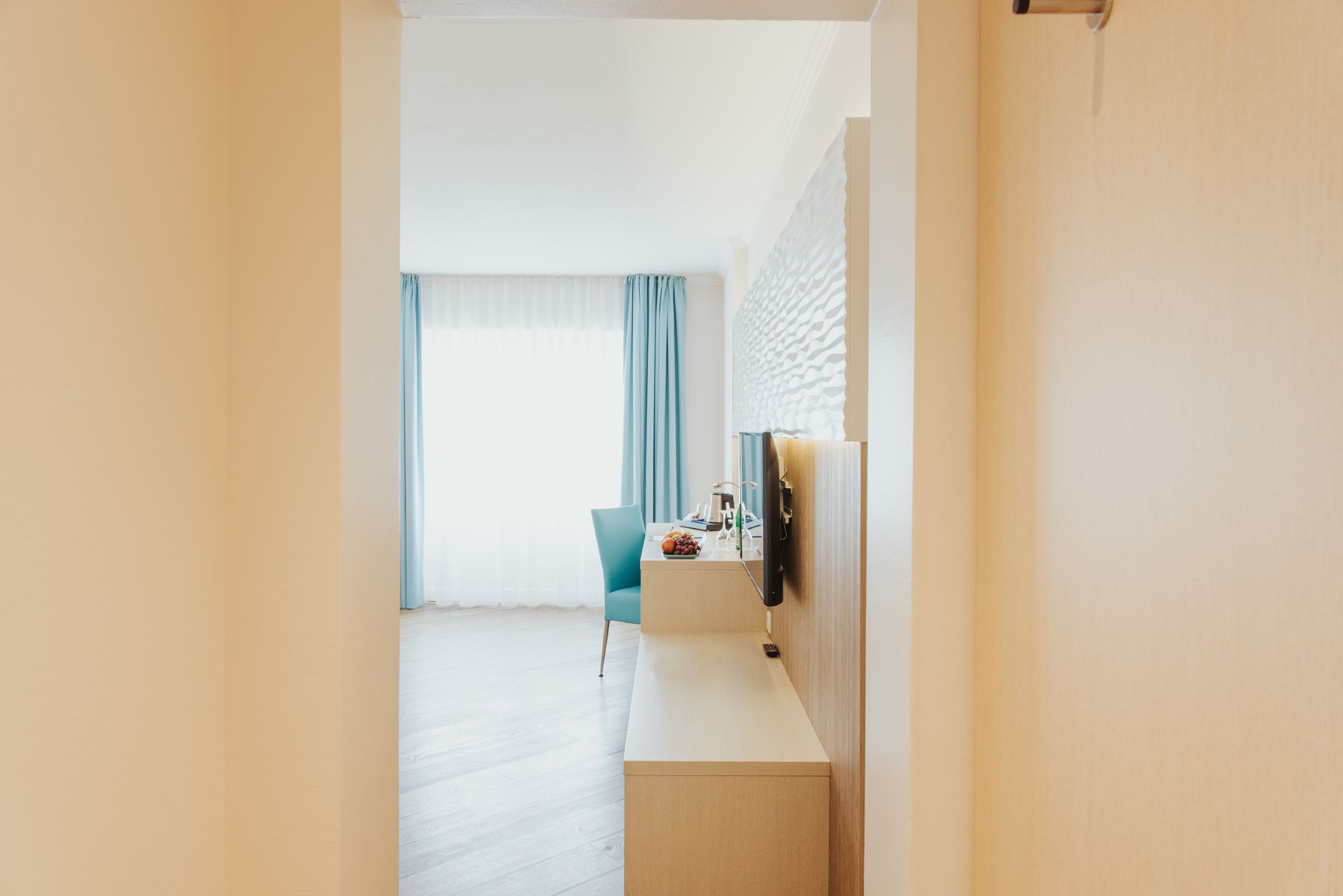 Ein Hotelzimmer mit Schreibtisch, Stuhl und Fernseher.