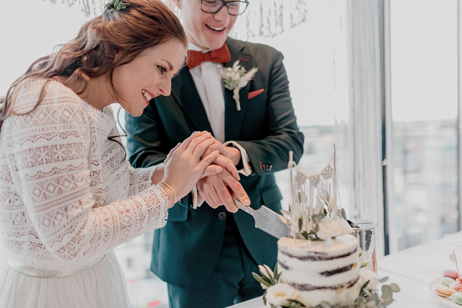 Braut und Bräutigam schneiden gemeinsam ihre Hochzeitstorte an.