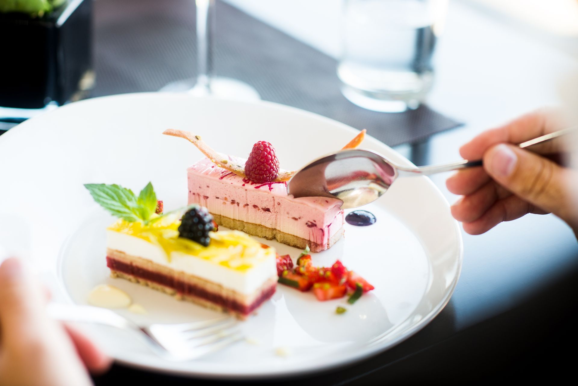 Eine Person isst ein Dessert mit einem Löffel auf einem Teller.