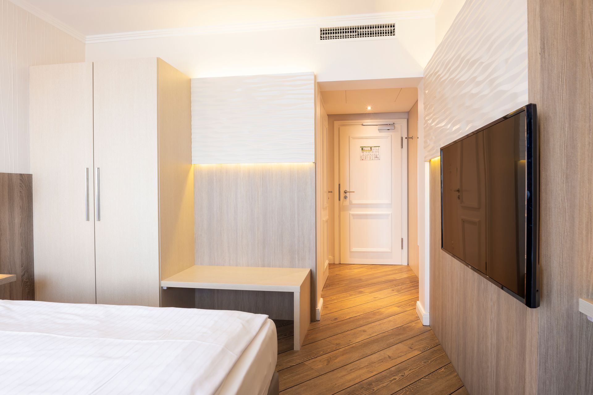 Ein Hotelzimmer mit einem Bett und einem Fernseher an der Wand.