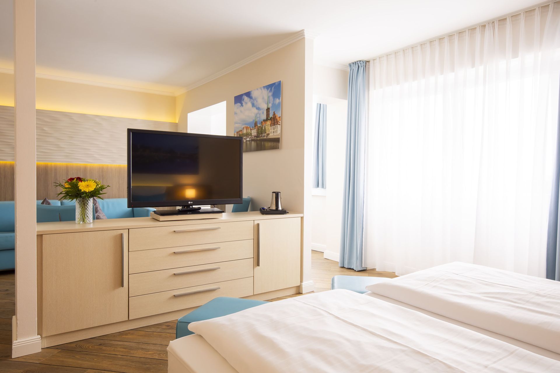 Ein Hotelzimmer mit zwei Betten und einem Flachbildfernseher.