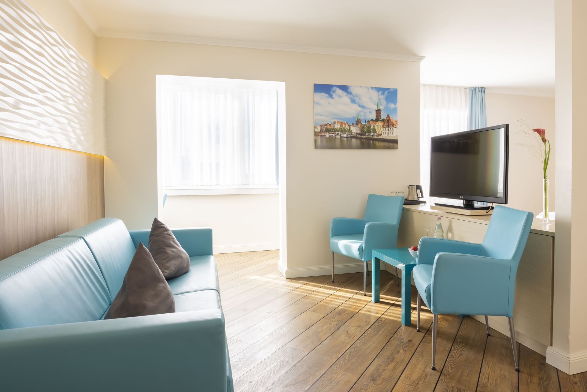 Ein Wohnzimmer mit Couch, Sesseln und Fernseher.