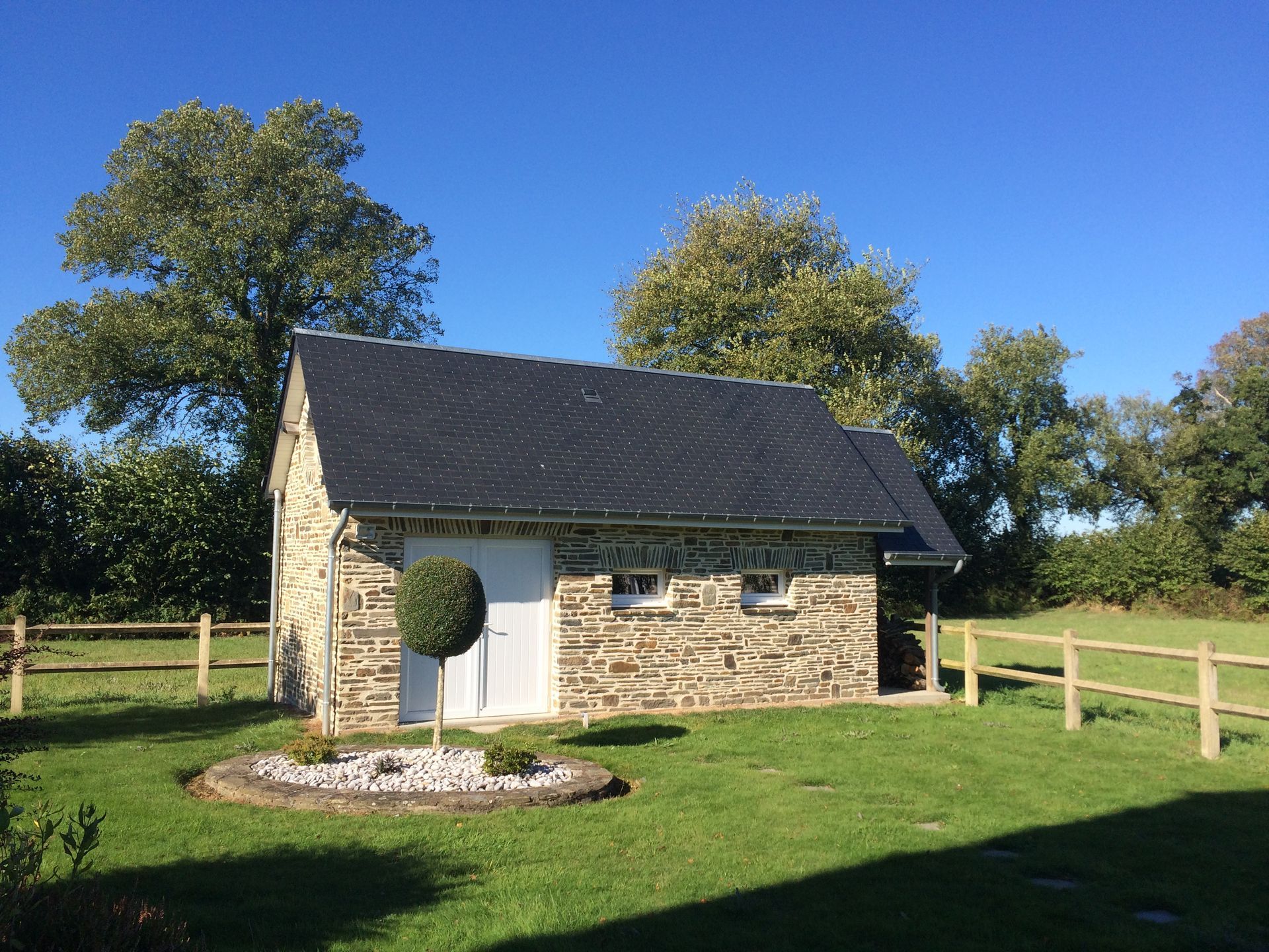 Dépendance dans un jardin avec façade en pierre