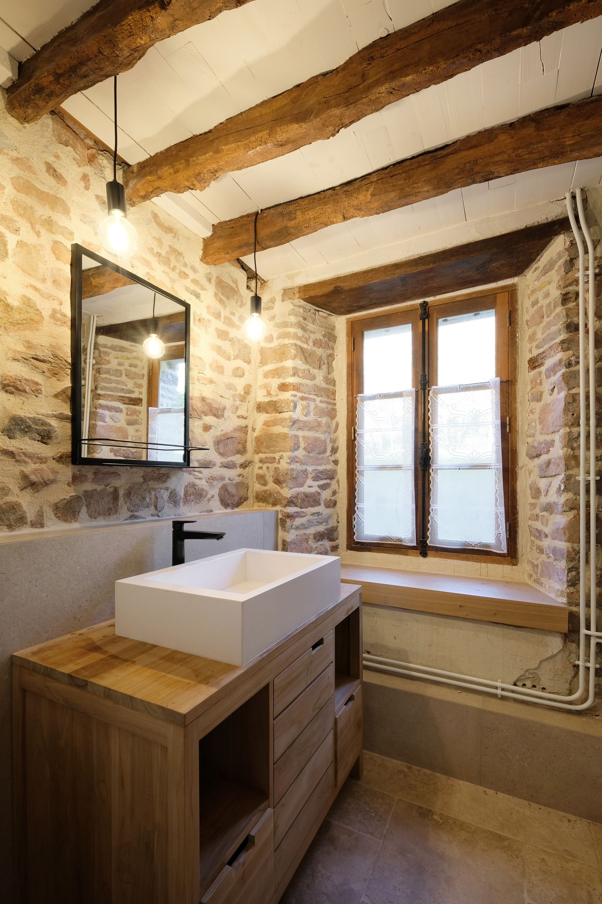 Salle de bains rénovée avec pierres apparentes et poutres au plafond