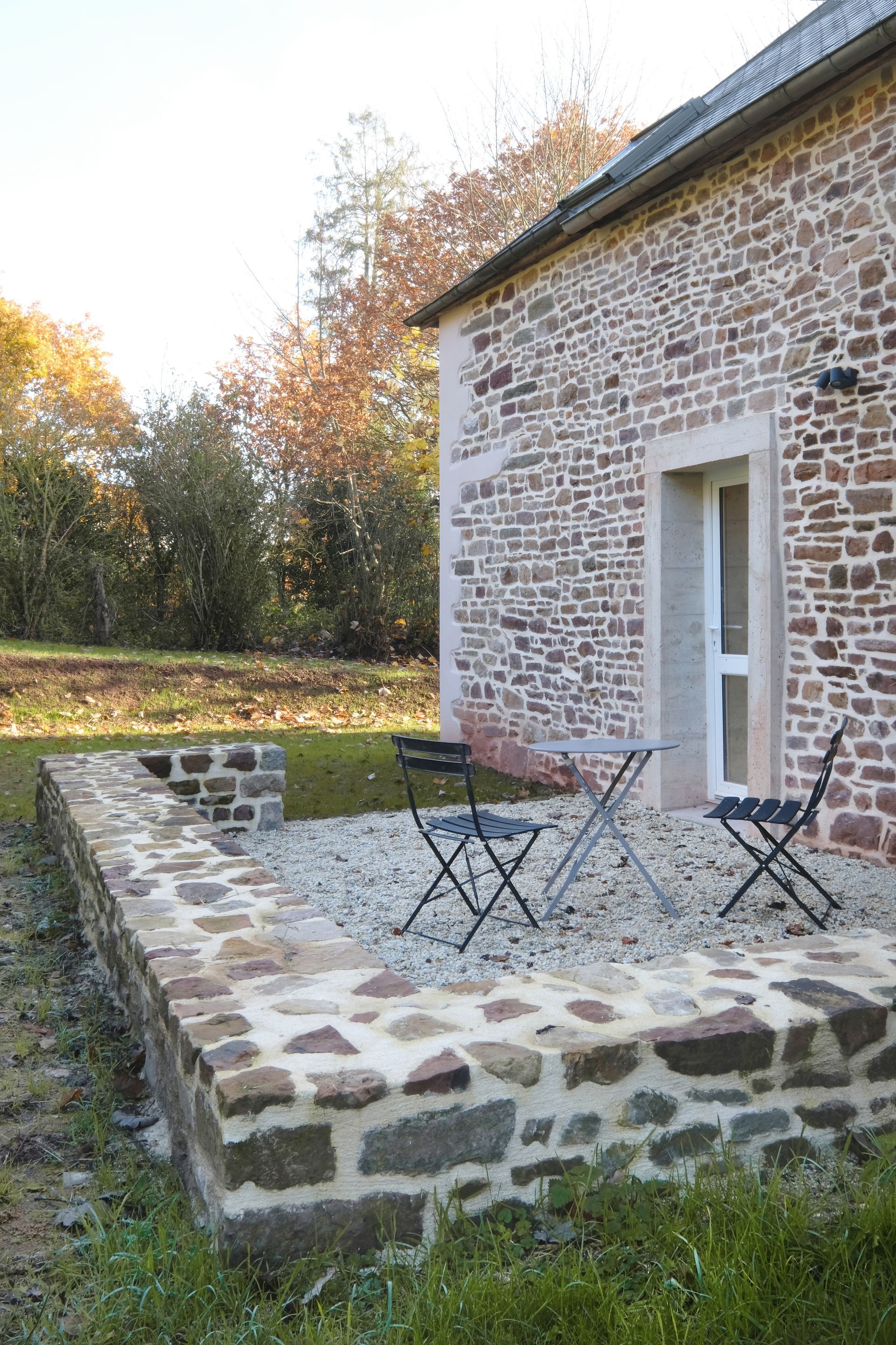 Terrasse d'une maison en pierre avec une table et deux chaises