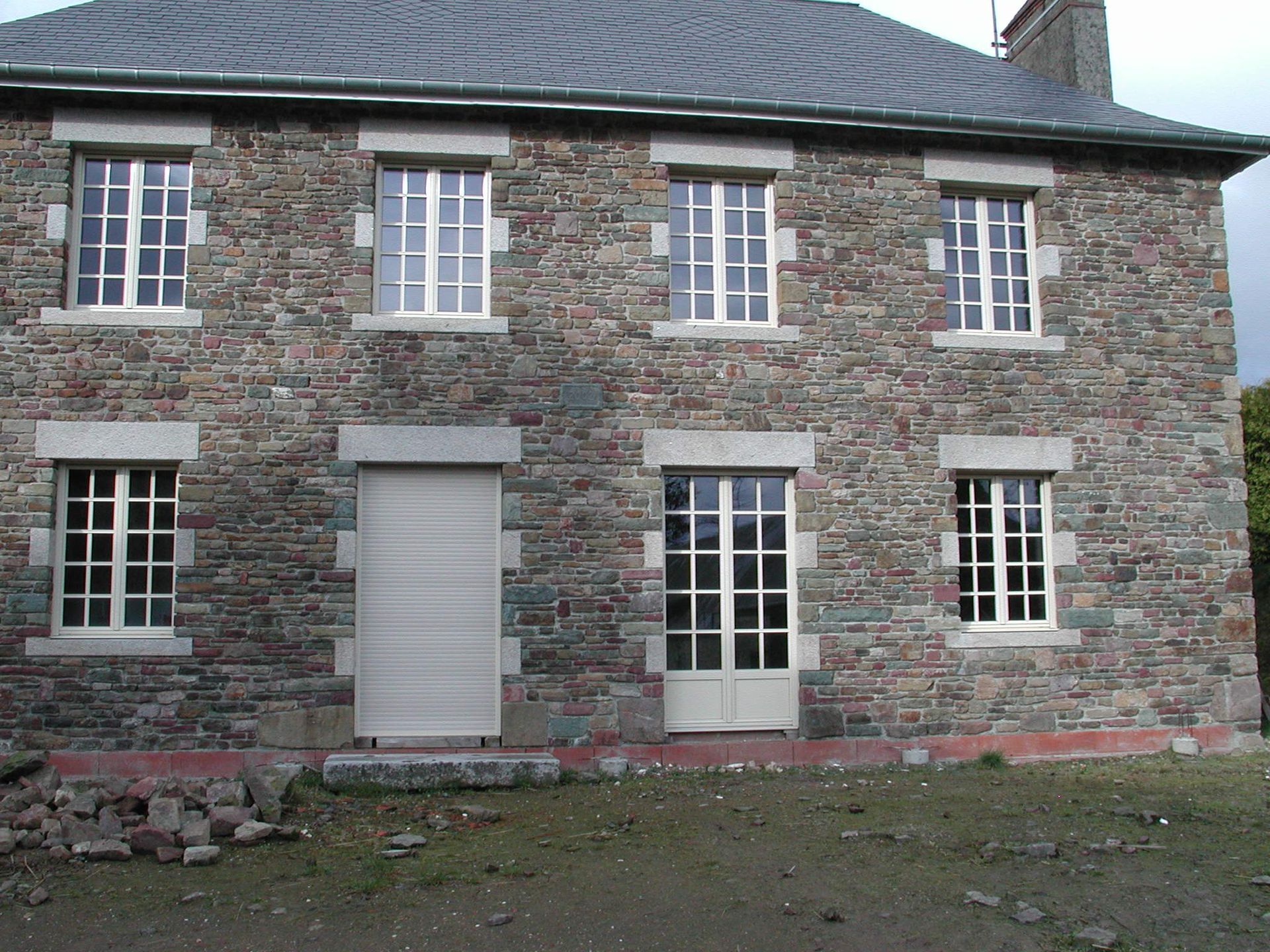 Façade d'une maison en pierre avec plusieurs fenêtres