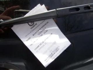 Una multa de estacionamiento adherida al limpiaparabrisas de un automóvil.