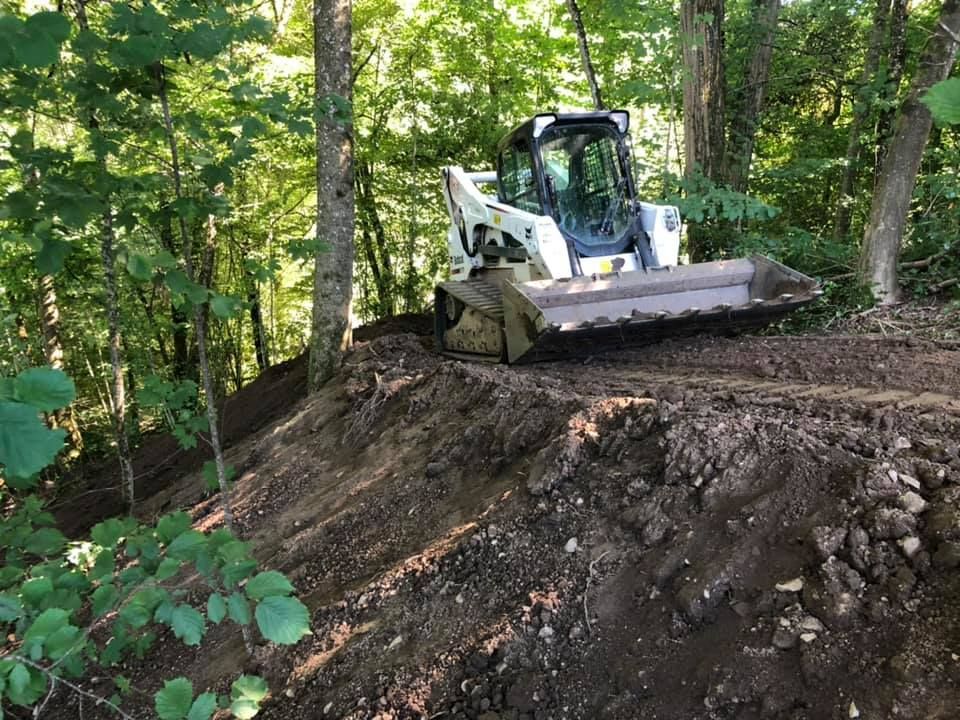 Engin sur un terrain arboré pentu. 