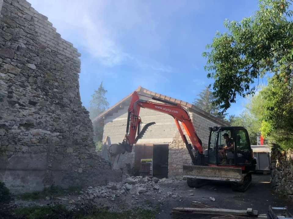 Engin de chantier rouge démolissant le mur d'une maison.