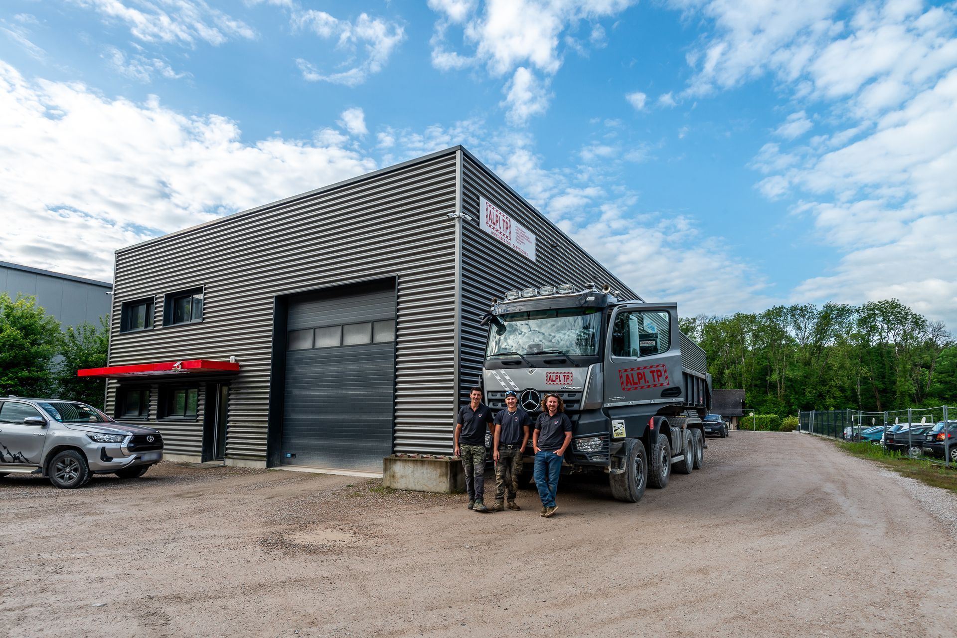 Bâtiment noir avec des professionnels qui posent devant un camion.