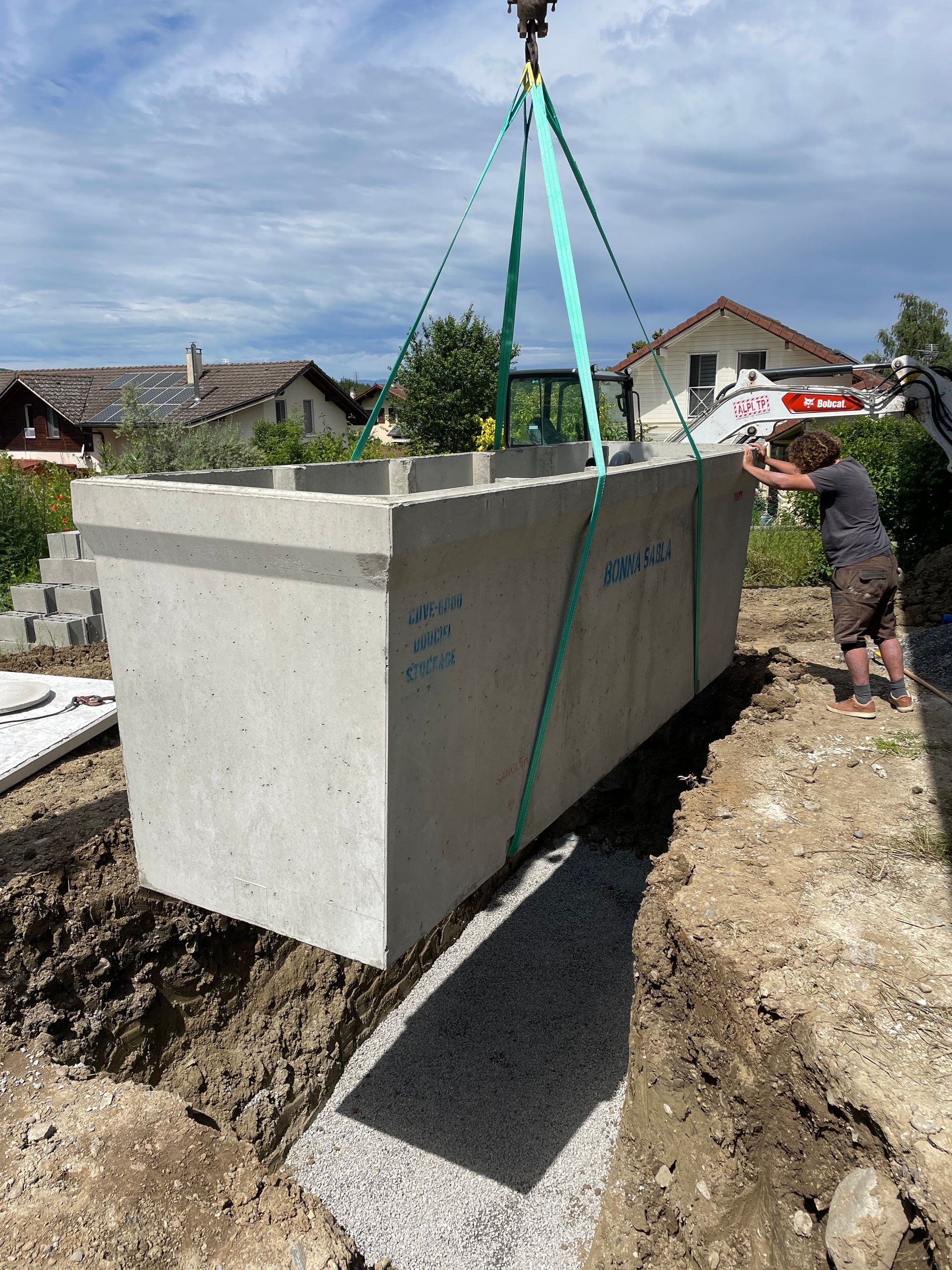 Professionnel installant une cuve de récupération d'eau dans une tranchée.