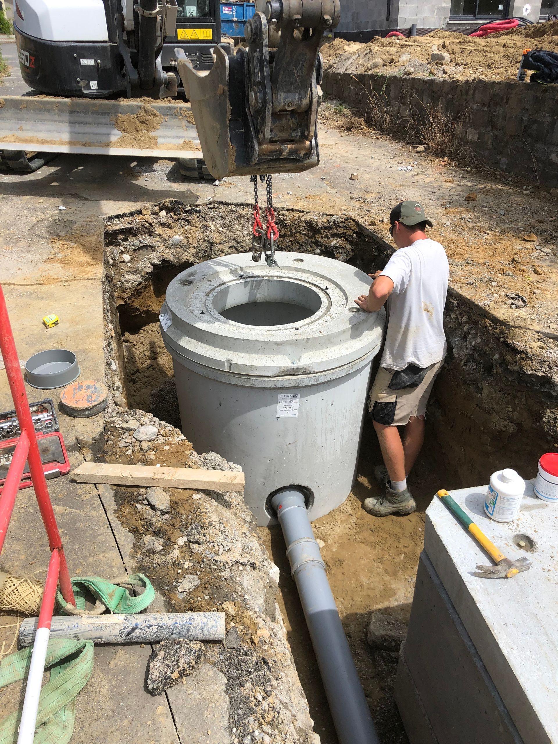 Professionnel dans une tranchée qui installe une cuve pour une bouche d'égout.