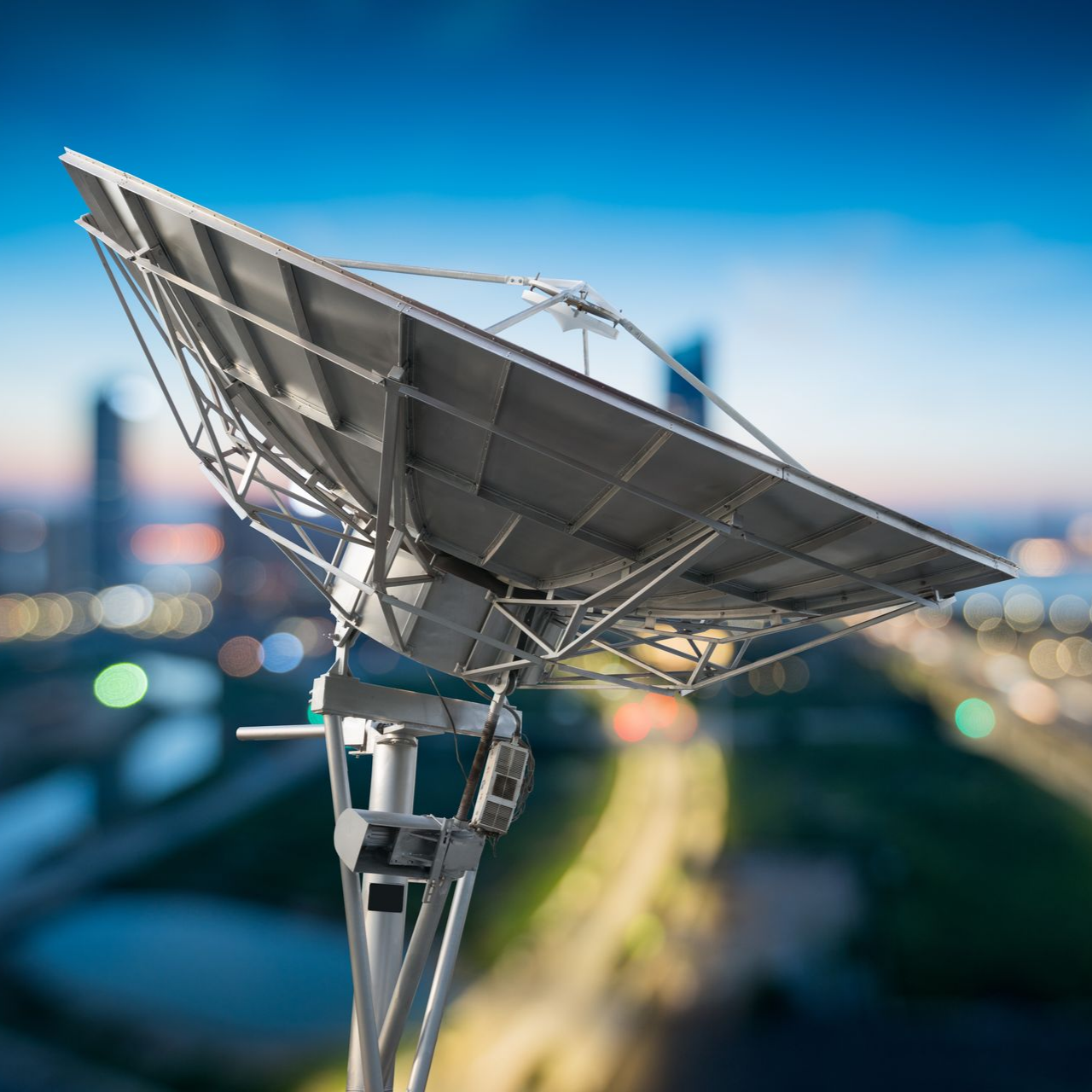 Antenne parabolique se détachant sur un paysage urbain flou.