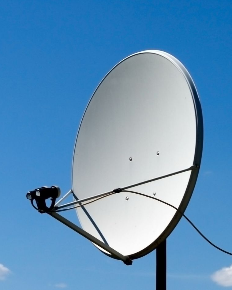 Antenne parabolique blanche sur fond de ciel bleu.