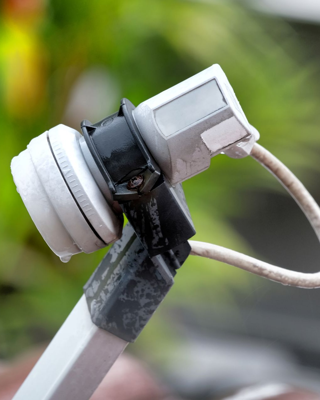 Gros plan sur un LNB (convertisseur de fréquence à faible bruit) d'une antenne parabolique avec un câble coaxial blanc.