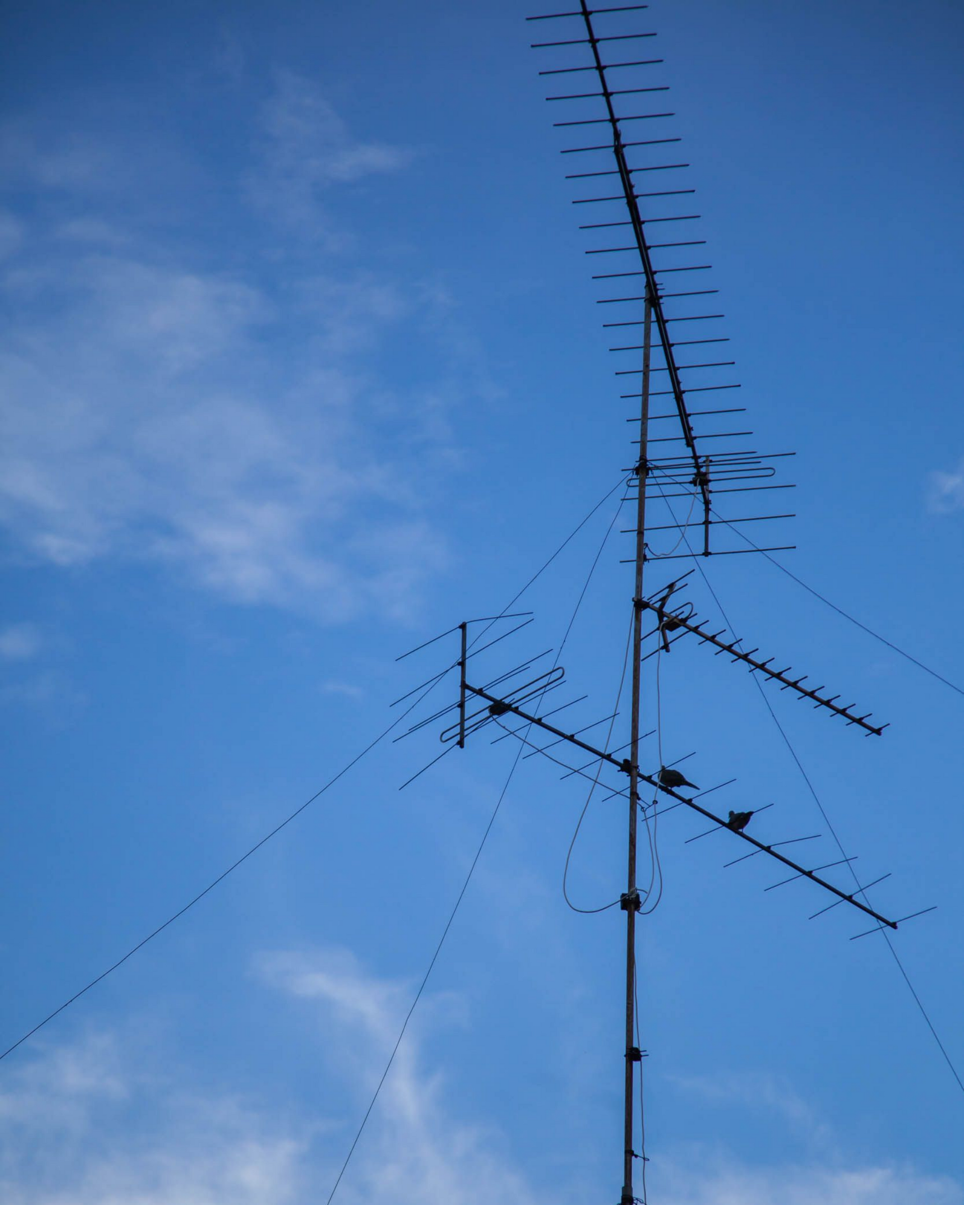 Antenne de télévision se détachant sur un ciel bleu partiellement nuageux.